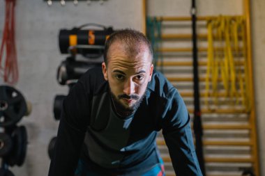 Genç adam spor salonunda çok fonksiyonlu egzersiz yapıyor.