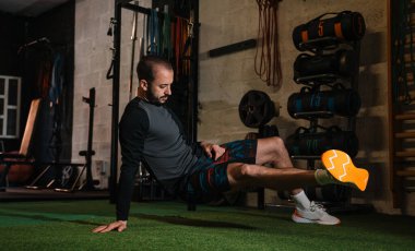 Genç adam spor salonunda esneme egzersizleri yapıyor.