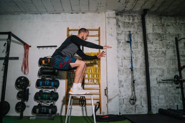 Genç adam spor salonundaki kutunun üstüne atlıyor.