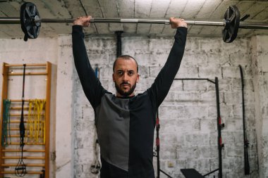 Genç adam spor salonunda ağırlık kaldırma