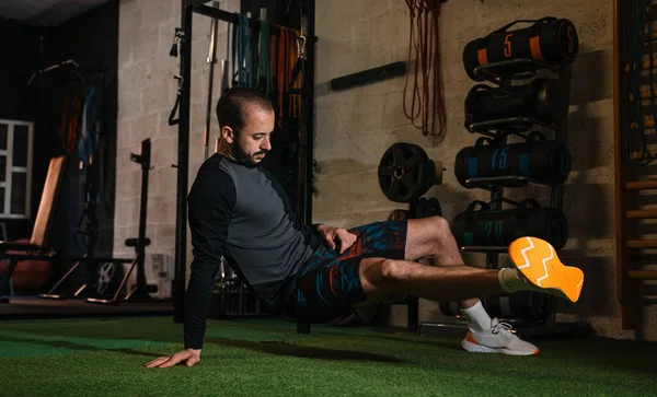 Genç adam spor salonunda esneme egzersizleri yapıyor.