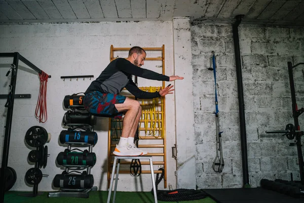 Genç adam spor salonundaki kutunun üstüne atlıyor.