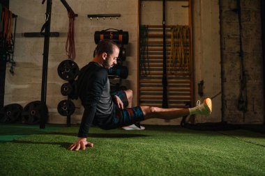 Genç adam spor salonunda esneme egzersizleri yapıyor.