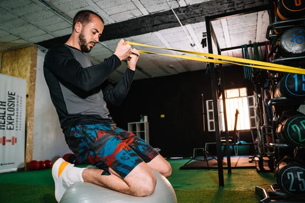 Genç adam spor salonunda çok fonksiyonlu egzersiz yapıyor.