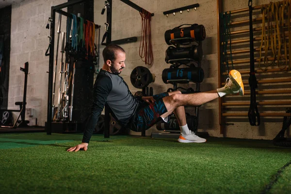 Genç adam spor salonunda esneme egzersizleri yapıyor.