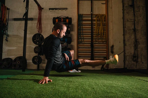 Genç adam spor salonunda esneme egzersizleri yapıyor.