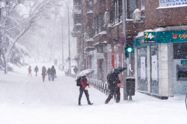 People on a city street covered in snow during heavy snowfall storm in Madrid clipart