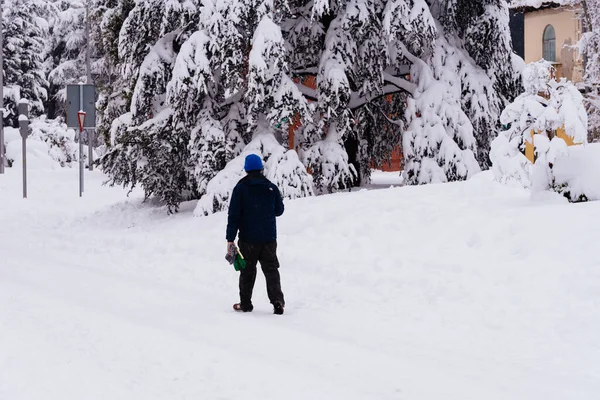 Man går på en stadsgata täckt av snö under kraftigt snöfall med fallna träd — Stockfoto