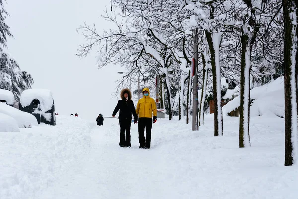 Man går på en stadsgata täckt av snö under kraftigt snöfall med fallna träd — Stockfoto