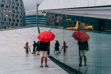 Oslo 'daki Opera binasında kırmızı şemsiyeli bir genç.