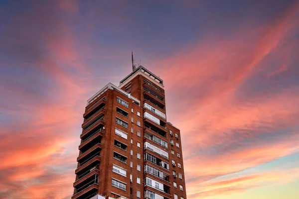 Низкий угол обзора старого жилого небоскреба против красочного неба заката — стоковое фото