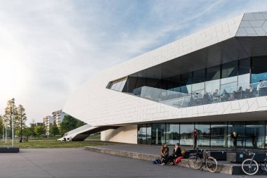 Amsterdam, Hollanda - 6 Mayıs 2022: Delugan Meissl Associated Architects tarafından tasarlanan Göz Filmi Müzesi. İnsanlar günbatımının tadını çıkarıyor