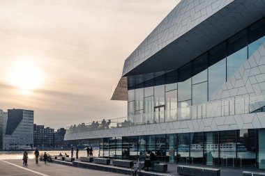 Amsterdam, Hollanda - 6 Mayıs 2022: Delugan Meissl Associated Architects tarafından tasarlanan Göz Filmi Müzesi. İnsanlarla dramatik turuncu gün batımını izle