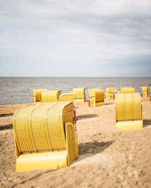 Kumsal ve Kuzey Denizi kıyısındaki Cuxhaven 'da tipik kapüşonlu plaj sandalyeleri. Yazın bulutlu bir günü. Almanya