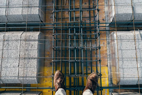 Architect checking a concrete floor slab with rebars in a residential building under construction. Construction industry and real estate market.