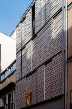 Madrid, Spain - October 17, 2020: New residential building amidst old buildings in Lavapies quarter. Facade with movable lattices