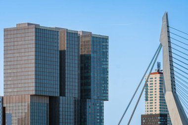 Rotterdam, Hollanda - 8 Mayıs 2022: De Rotterdam Gökdeleni Rem Koolhaas tarafından tasarlandı ve Erasmusbrug Köprüsü gökyüzüne karşı inşa edildi. Çağdaş mimari. Telefoto lens görüntüsü