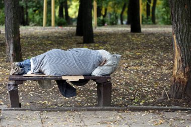 Evsiz, parkta bir bankta uyuyor.