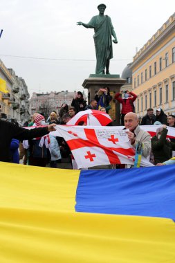 Odessa, Ukrayna 20 Şubat 2022 'de ellerinde büyük bir Ukrayna bayrağı tutarken, diğer insanlar Dük de Richelieu anıtının arka planında Gürcistan bayrağını tutuyor.