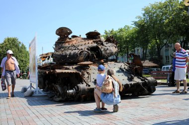 Rivne, Ukrayna 29 Haziran 2022 Anne ve bir çocuk ve diğerleri Rusya Federasyonu 'nun yanmış askeri teçhizatına bakıyorlar.