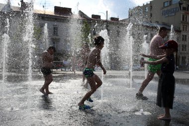 Lviv, Ukrayna, 30 Haziran 2022. Çocuklar, Solomia Krushelnitskaya 'nın adını taşıyan Lviv Ulusal Akademik Opera ve Bale binasının yakınındaki bir çeşmede yıkanırlar.