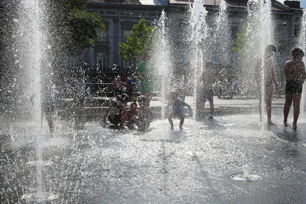 2022年6月30日 乌克兰利沃夫 孩子们在利沃夫国家学术歌剧和芭蕾舞团大楼附近的一个喷泉中洗澡 这个喷泉是以Solomia Krushelnitskaya命名的 — 图库照片