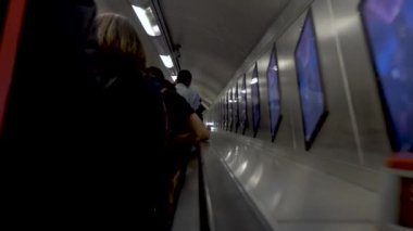 Londra 'da yürüyen merdivenden çıkan banliyö çalışanlarının arkasında duruyor.