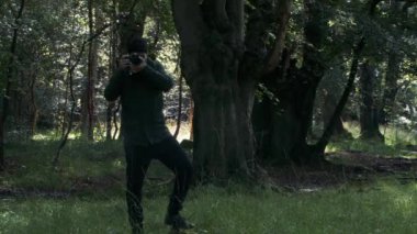 Erkek fotoğrafçı, Woodland Ormanı 'nda yürüyor ve fotoğraf çekiyor. Kilitli