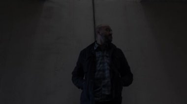 Kel etnik azınlık erkek, karanlık alt geçit tünelinde yan yana bakıyor. Düşük Açı, Statik Çekim