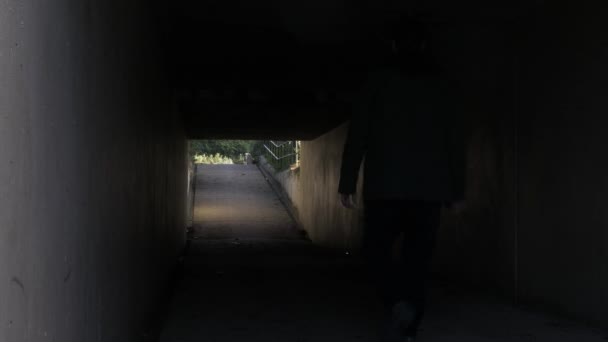 Silhouette Male Walking Exiting Dark Underpass Tunnel Low Angle Locked — Stock Video