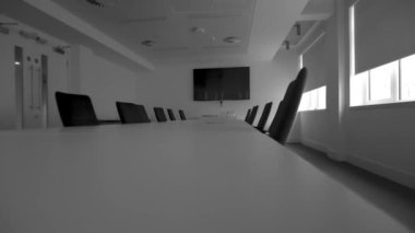 View of a modern conference room with white interior, chairs, tables, and TV for the purpose of video conferencing and tele meetings.