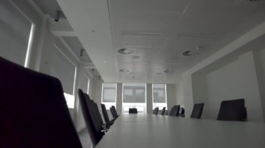 View of Modern conference room with white interior, black chairs, white long table and big windows with curtains. Roof fitted with AC vents and lights.