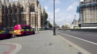 POV, Abingdon Caddesi boyunca yürürken vuruldu, Lady Chapel 'in (solda) önünde park etmiş iki polis aracı ve Parlamento Binaları için yeniden yapılanma projesinin iskelesi (sağda), Londra, İngiltere