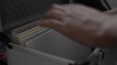 Metal bir koruyucu çantayı açarken ve koleksiyonunda özel bir albüm ararken bir DJ 'in ellerini yakın çekim yap 