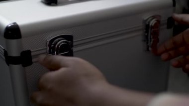 Bir DJ 'in gümüş metal çantasının mandallarını açarken yakın plan çekimleri değerli plak koleksiyonunu gözler önüne seriyor.