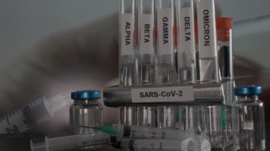 Laboratuvar Test Tüpleri Arka plandaki Vial Bottle 'dan aşı elde etmek için şırınga kullanan Alfa Gamma Delta Beta ve Omicron Varyantlarını etiketledi.