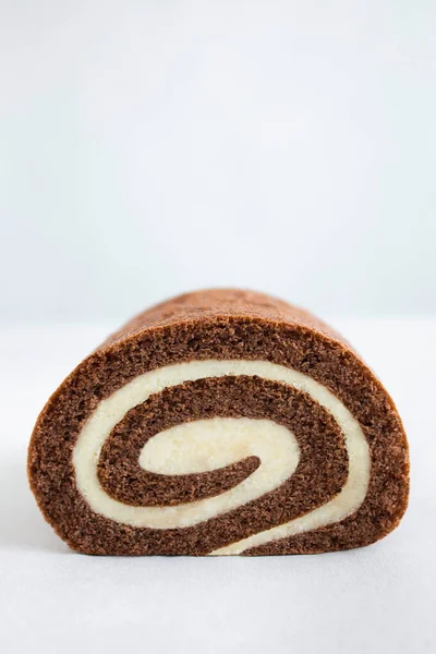 Chocolate swiss roll closeup isolated on white background. Delicious homemade biscuit with dark chocolate and cream filling. Dessert sweet food for product presentation, mockup, photo, posters and wallpapers. Minimalism concept with copy space.