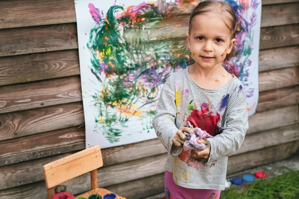Klein meisje reinigt borstel met een doek na het schilderen — Stockfoto