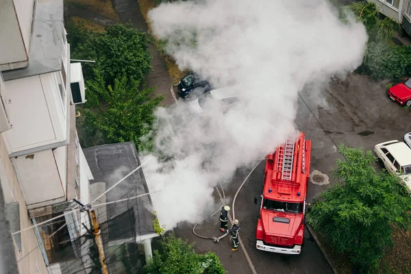 Пожарная машина возле жилого дома и тушит пожар в городе — стоковое фото