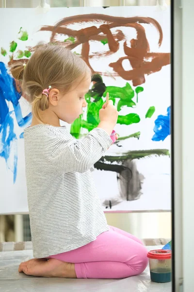 Schattig klein meisje schilderen met verschillende kleuren thuis — Stockfoto