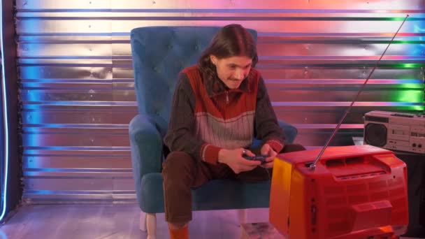 Muž hraje retro staré video TV hry v neonovém stylu interiéru — Stock video