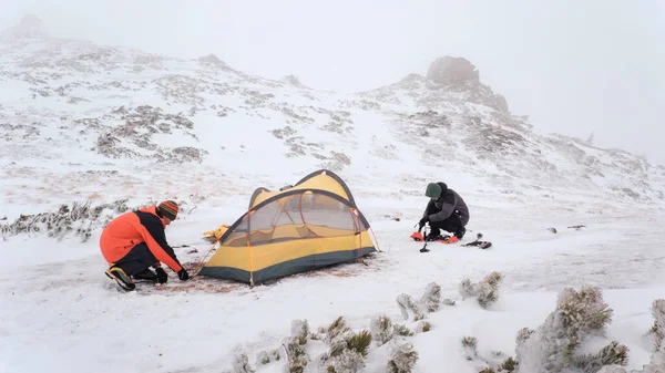 Tourist put up tent in winter mountains while hiking — Stok fotoğraf