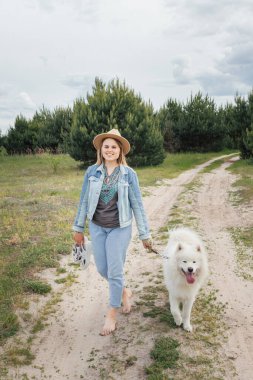Genç ve güzel bir kadın parktan beyaz köpeğiyle çıkıyor..