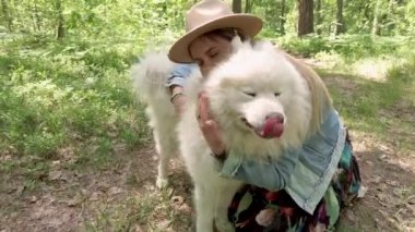 Young beautiful woman hugging her dog samoyed after walking in forest