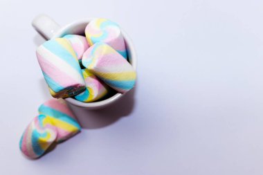 Beyaz arka planda bir fincan dolusu renkli lokum şekeri.