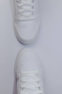 Beyaz arka planda iki beyaz spor ayakkabısının üst görünümü - dikey