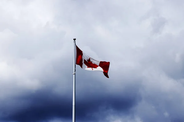有戏剧性云彩的旗杆上的加拿大国旗 — 图库照片