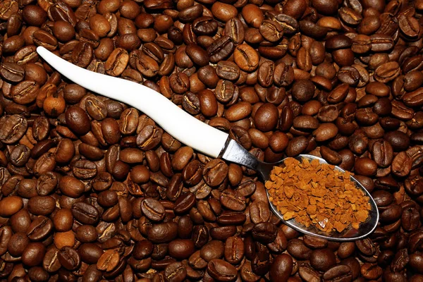 Fasulye arkaplanında hazır kahve olan bir kaşık.