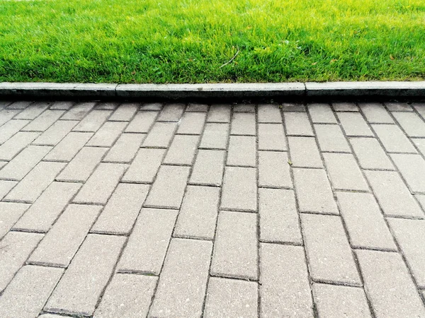 Yeşil bir çimenliğin arka planında asfalt döşeme