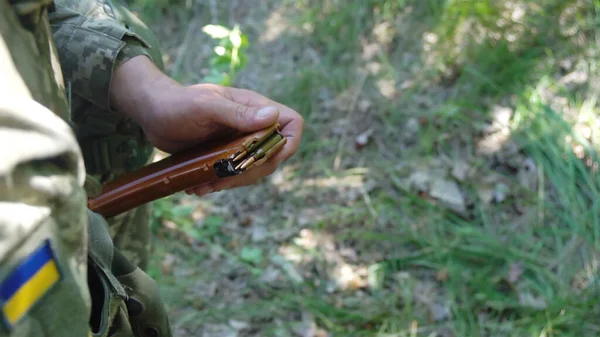 Ukrainian military man loads machine gun magazine with cartridges